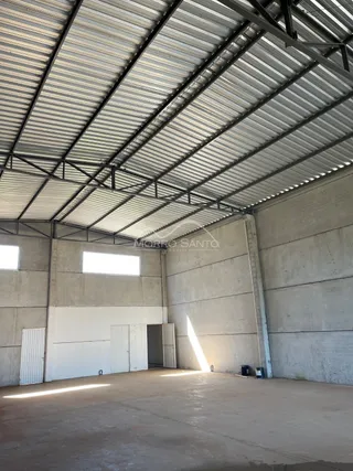Foto do interior de um espaço com teto metálico e paredes de concreto aparente.