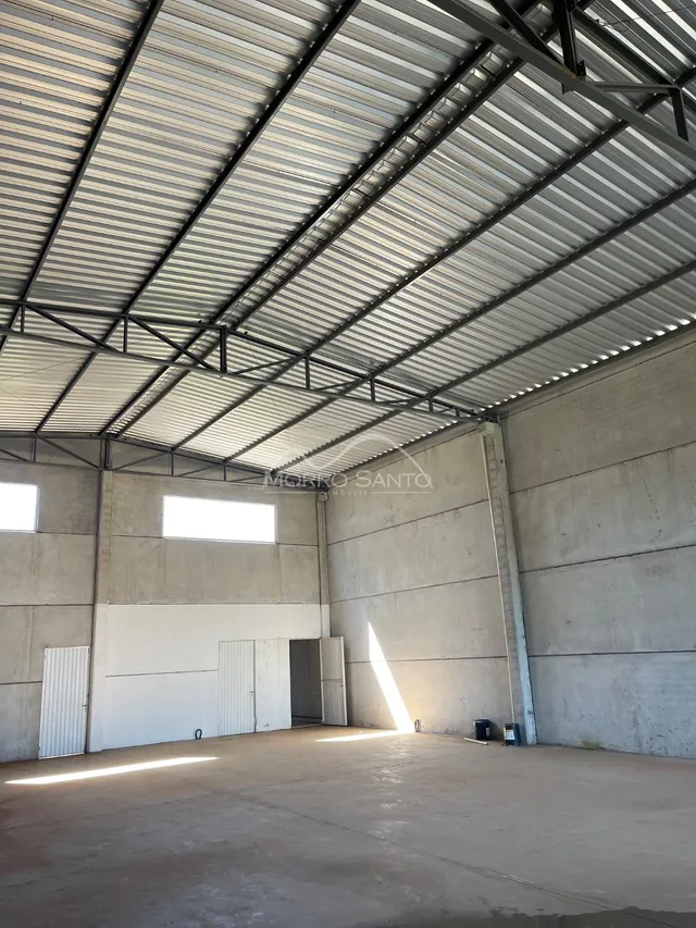 Foto do interior de um espaço com teto metálico e paredes de concreto aparente.