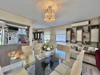 Sala de estar com móveis claros e espelho refletindo a cozinha.