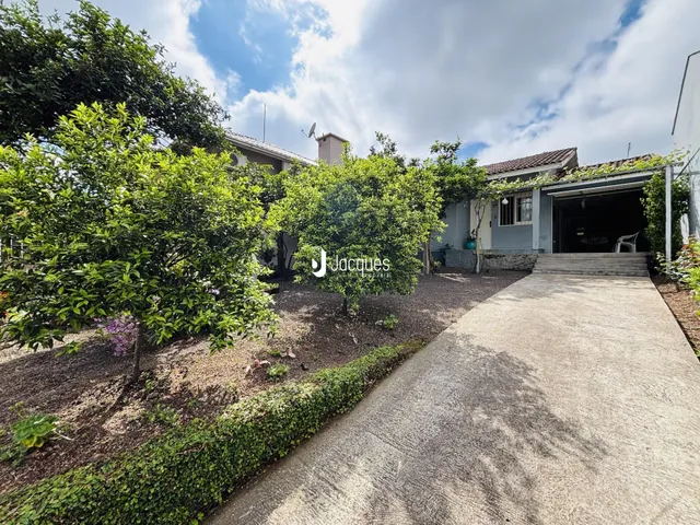 Vista da fachada de uma residência com jardim e entrada pavimentada.
