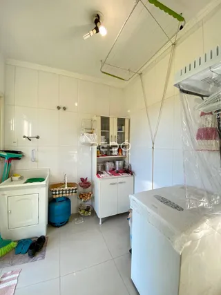 Interior de uma cozinha com armários brancos e piso de cerâmica.