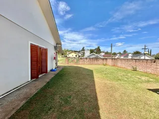 Fachada de uma casa com jardim gramado e muro de tijolos.