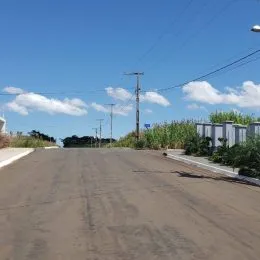 Vista da rua em Lajeado, Brasil, com postes de eletricidade e vegetação ao fundo.