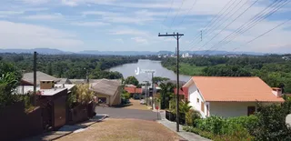 Vista externa de uma propriedade com paisagem de rio e vegetação densa.