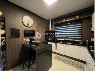 Interior de uma sala de estar com detalhes em madeira e cozinha moderna.