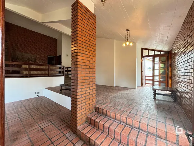 Vista interna de uma sala com piso de cerâmica e paredes de tijolo aparente.