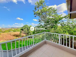 Vista panorâmica de um jardim e campos sob um céu azul.