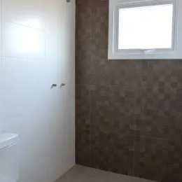 Vista parcial de um corredor interno com parede texturizada e uma porta branca.
