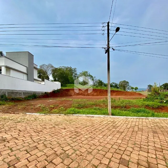 Vista externa de uma propriedade com área pavimentada e terreno inclinado.