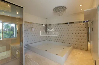 Quarto com cabeceira estofada e lustre em um imóvel no Brasil.