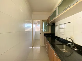 Hall de cozinha com revestimento branco e armários de madeira.