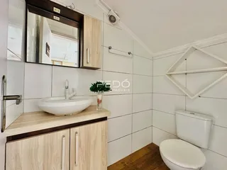 Foto de um banheiro com revestimento de azulejos brancos e bancada de madeira.