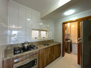 Cozinha com armários de madeira e bancada de granito em um imóvel no Brasil.