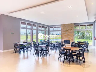 Sala de jantar ampla com mesas e cadeiras voltadas para a área externa.