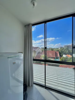 Ambiente interno com grande janela oferecendo vista para casas no entorno.