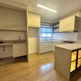 Ambiente interno com armários brancos e piso de madeira clara.