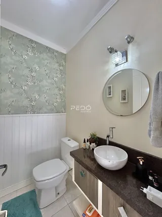 Banheiro com revestimento floral na parede e bancada de granito.
