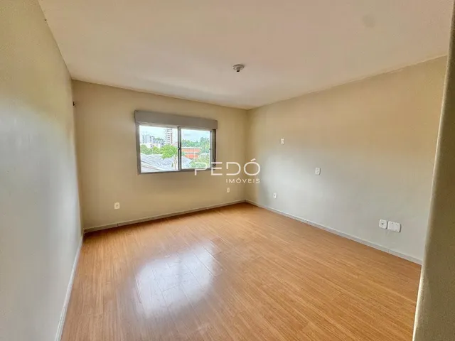 Sala de estar com piso de madeira clara e janela para a cidade.