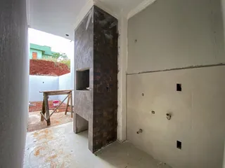 Vista interna de uma área com estrutura de tijolos escuros e paredes brancas.