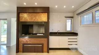 Interior da cozinha com revestimento de tijolos e armários brancos.