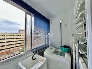 Vista interna de um cômodo com janela e máquina de lavar roupa.
