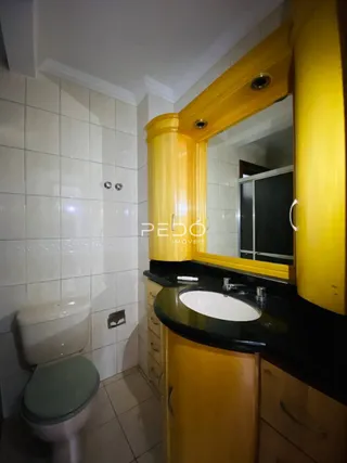 Foto de um banheiro com revestimento cerâmico e armário amarelo.