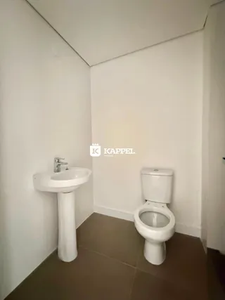 Banheiro com pia de pedestal e vaso sanitário brancos.