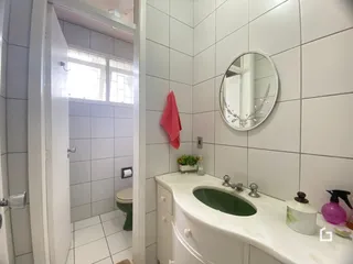 Banheiro com revestimento cerâmico branco e bancada de pia.