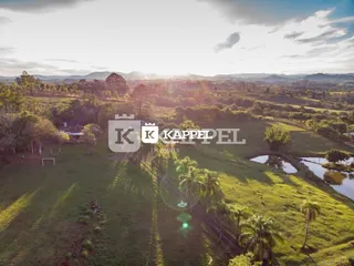 Vista aérea de uma paisagem rural com campos verdes e corpo d'água.