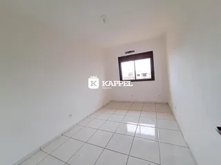 Um corredor amplo com piso de cerâmica e uma janela no final da sala.