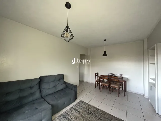 Sala de estar com sofá cinza e piso de cerâmica.