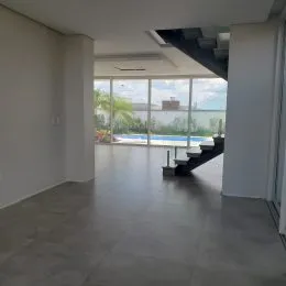 Ambiente interno amplo com piso de concreto e vista para área externa com piscina.
