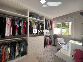 Um quarto com estantes brancas e roupas penduradas, apresentando um ambiente organizado.