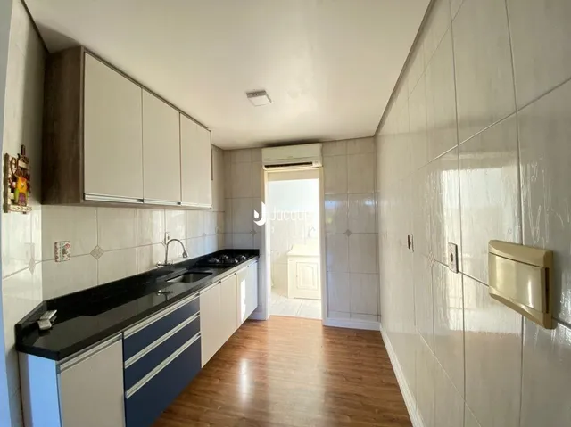 Vista interna de uma cozinha com revestimento cerâmico e piso de madeira.