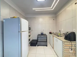 Cozinha com armários brancos e piso de cerâmica.