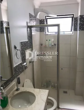 Foto de um banheiro com box de vidro e azulejos brancos.