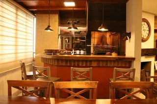 Uma vista interna de uma cozinha com balcão de madeira e cadeiras de madeira.