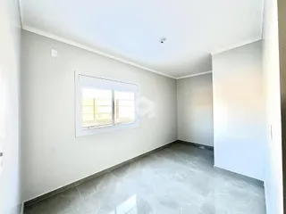 Uma sala interna com paredes brancas e piso de cerâmica clara.