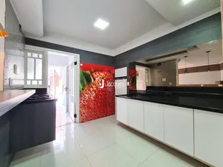 Vista da cozinha moderna com armários brancos e bancadas escuras.