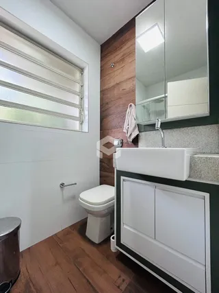 Foto de um banheiro interno com piso de madeira e louças sanitárias.