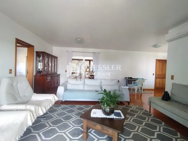 Sala de estar com piso de madeira e tapete no interior de uma residência.