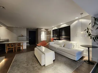 Sala de estar ampla com sofá branco e piso de madeira em um apartamento no Brasil.