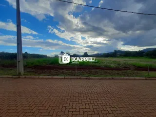 Vista de uma paisagem rural com campos verdes e montanhas ao fundo.