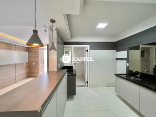 Uma cozinha moderna com ilha e armários em tons neutros.