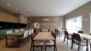 Uma sala de jantar com mesa de madeira e área de cozinha visível.