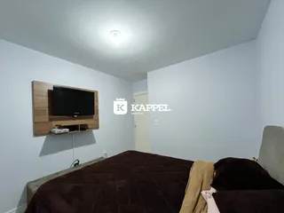 Foto de um quarto com cama e televisão montada na parede.