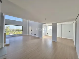 Sala de estar ampla com piso de madeira clara e vista para a paisagem.