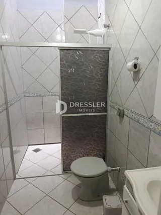 Interior de um banheiro com revestimento cerâmico branco.