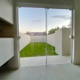 Porta de vidro que dá acesso a um gramado verde no exterior.