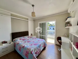 Quarto com cama e móveis brancos em um apartamento.